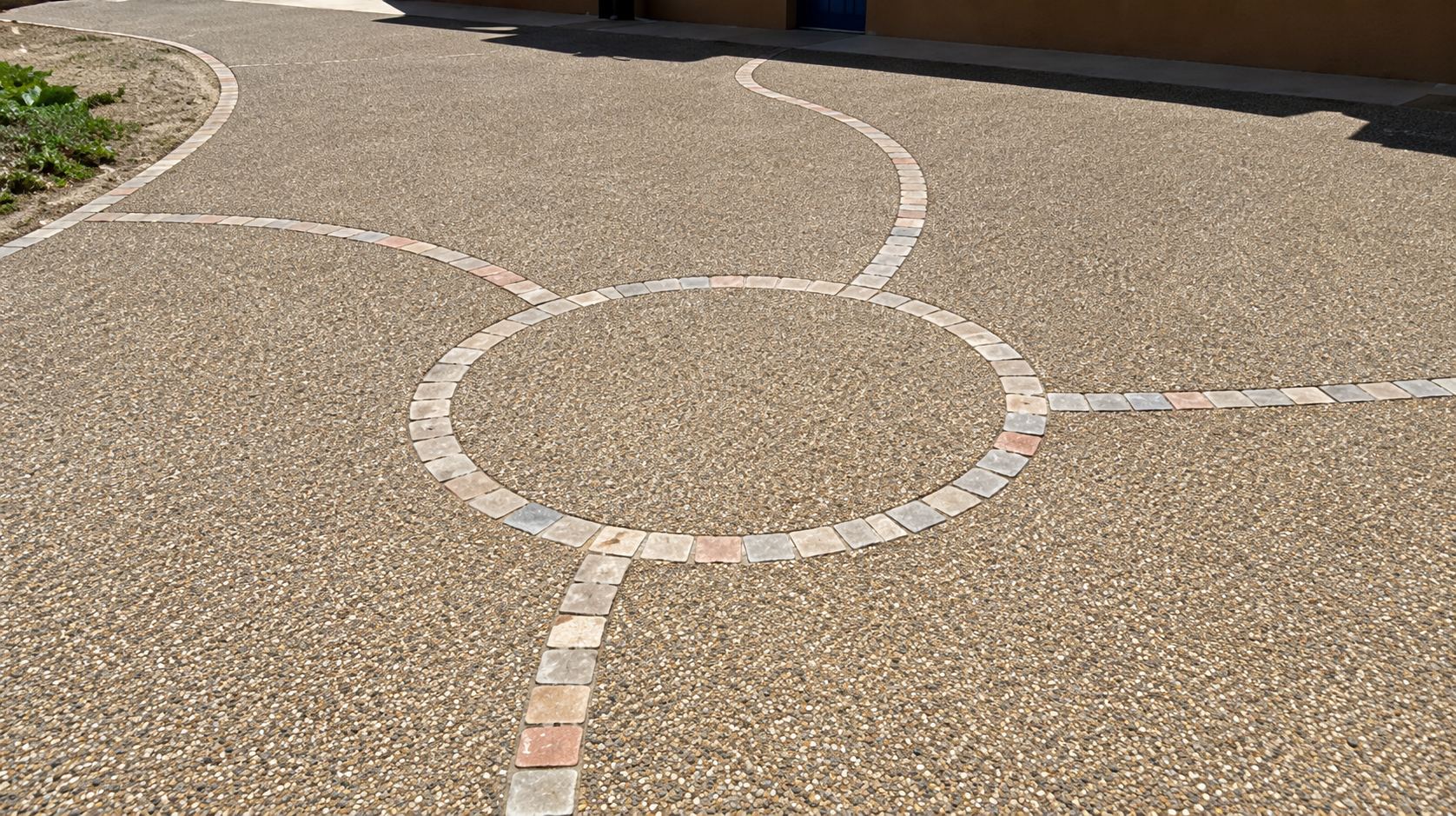 Sol en béton désactivé de teinte beige orné de cercles et de lignes en pierre claire formant un motif décoratif.