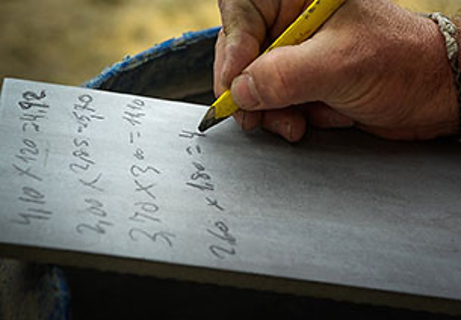 Artisan calculant des mesures au crayon sur une dalle grise