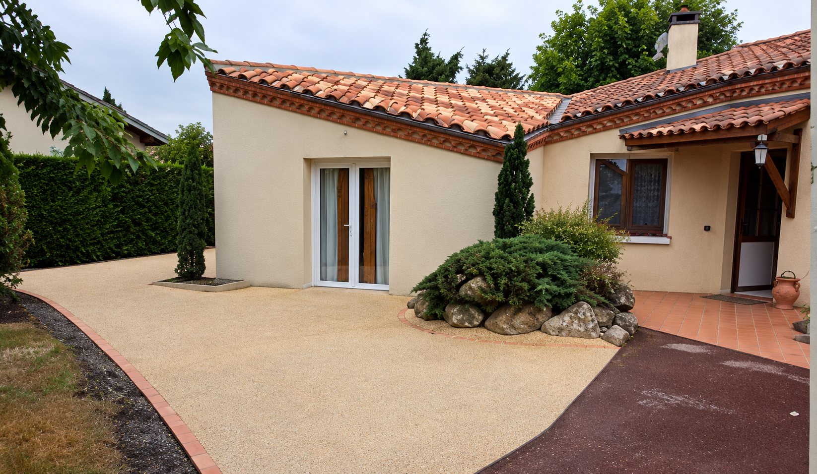 Maison de plain-pied avec allée de gravier lavé et jardin