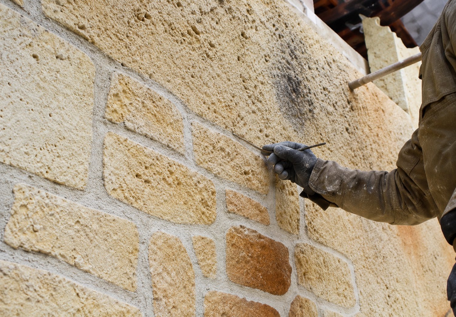 Ouvrier réalisant les joints d'un mur en pierre de taille